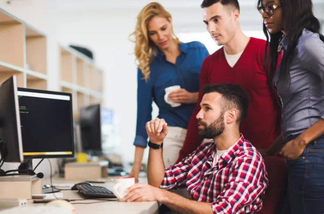 Four employees around a desktop computer